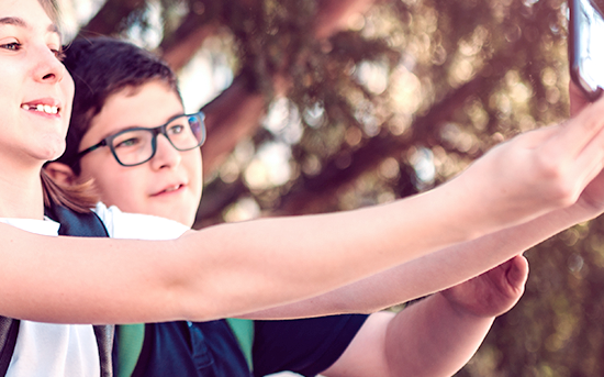 Kinder halten ein Smartphone und fotografieren sich.